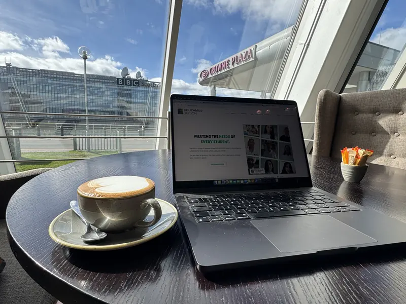 The Educamus Tuition website open on a laptop at a cafe table